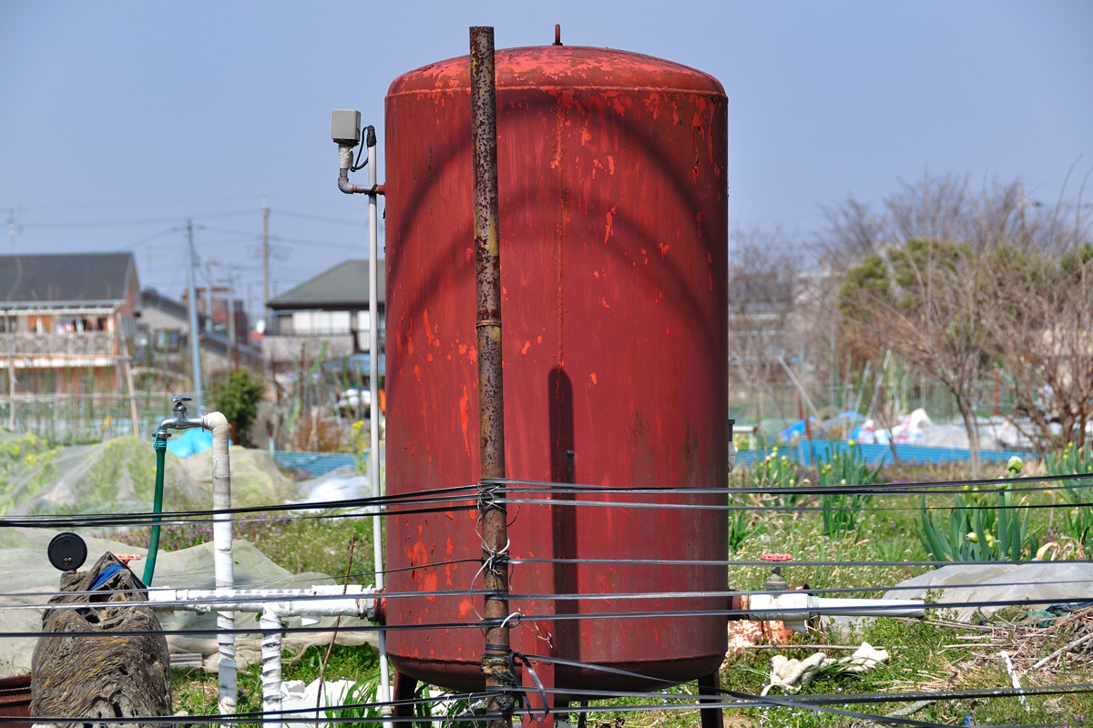 春の陽を浴びる赤い鉄製タンク