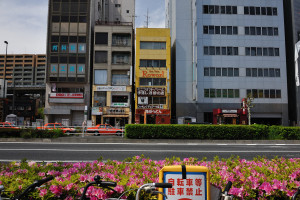 水神森近くの黄色い建物の近くをオレンジ色のタクシーが続く